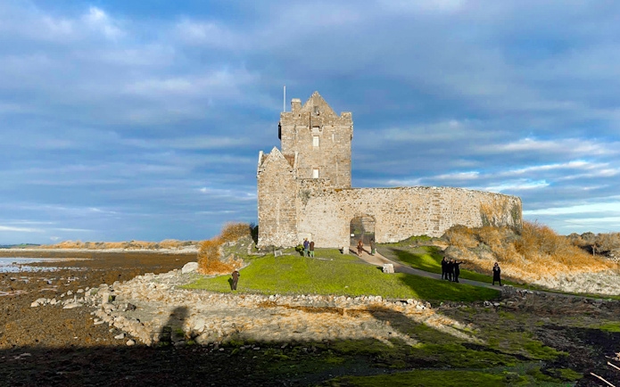 Dunguaire Castle in Ireland with visitors exploring the grounds.