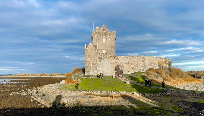 Dunguaire Castle in Ireland with visitors exploring the grounds.