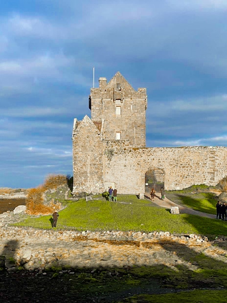 Dunguaire Castle in Ireland with visitors exploring the grounds.