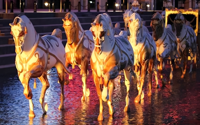 Illuminated horse statues in water at Land of Legends Night Show boat parade.