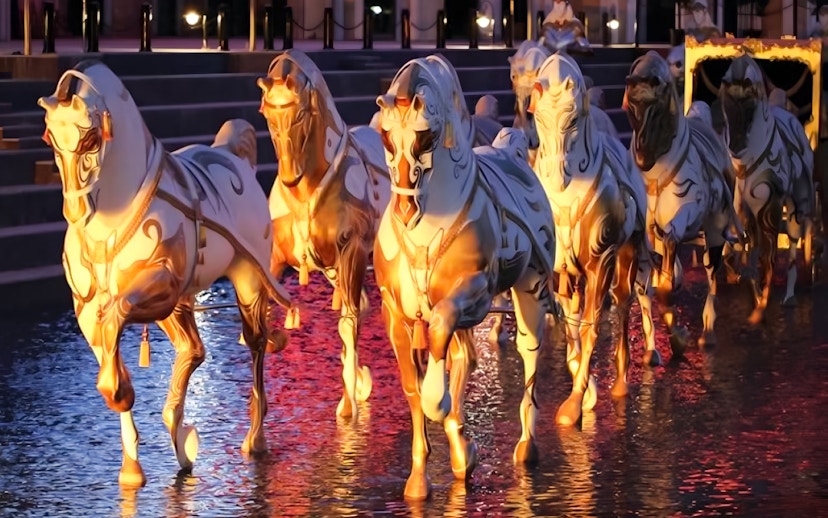 Illuminated horse statues in water at Land of Legends Night Show boat parade.