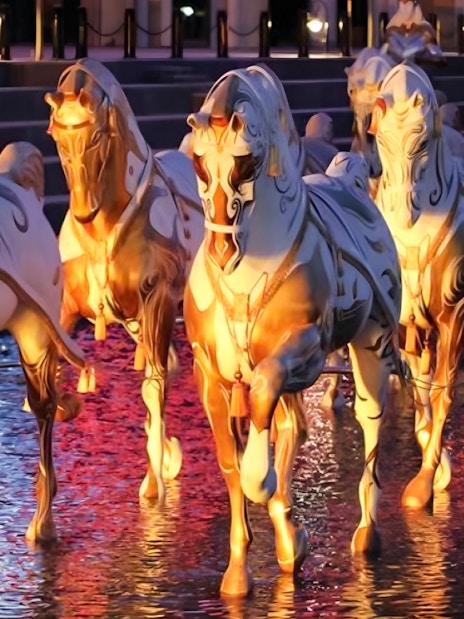 Illuminated horse statues in water at Land of Legends Night Show boat parade.