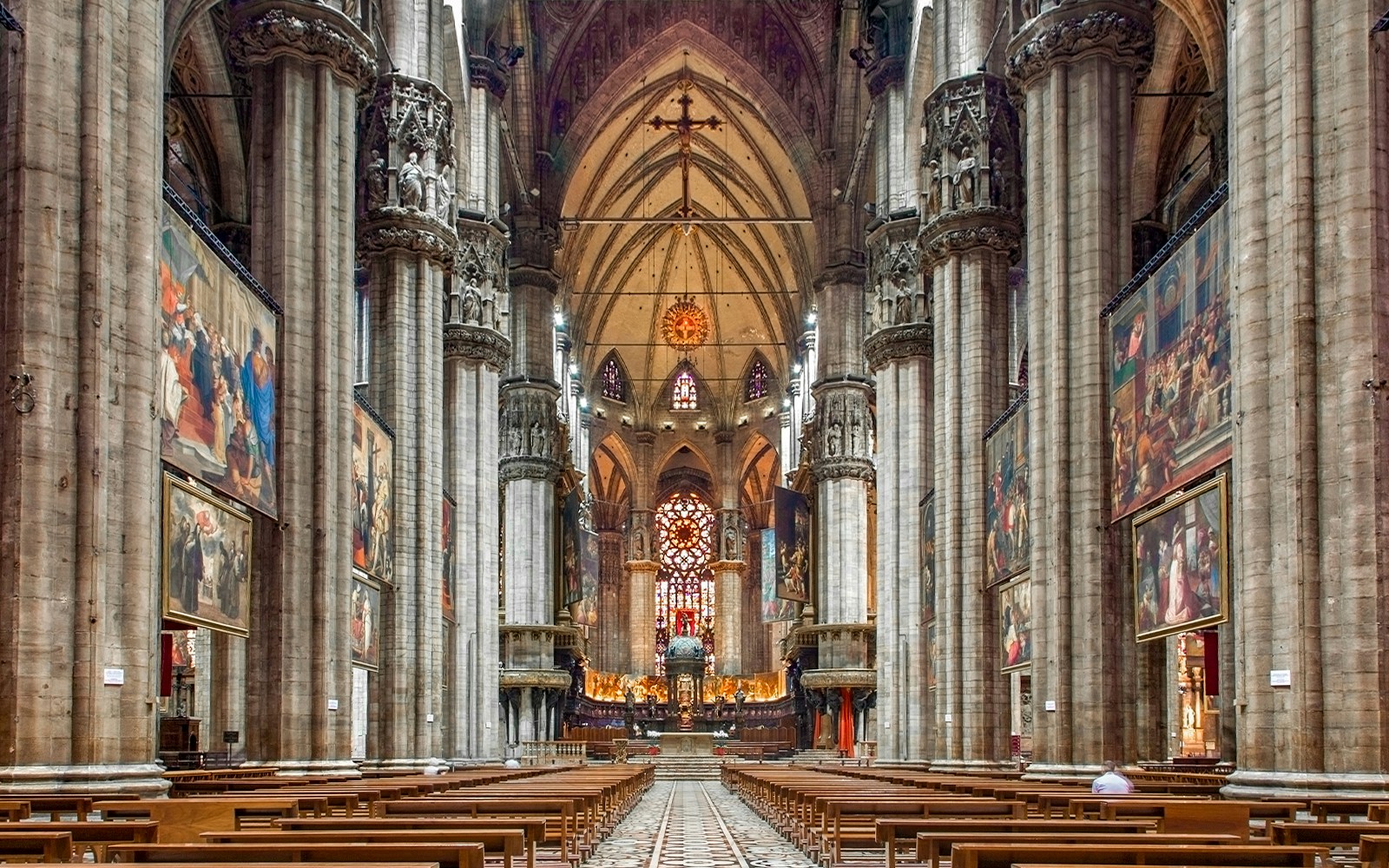 Interiors of the Duomo Milan Cathedral with ornate columns and stained glass windows.