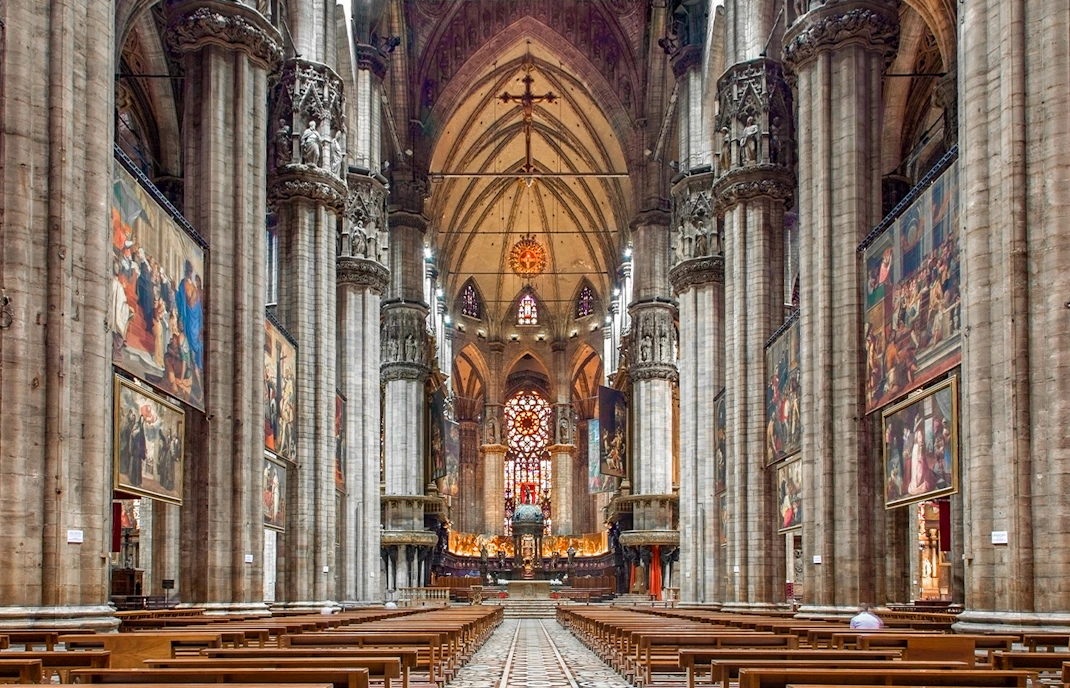 Interiors of the Duomo Milan Cathedral with ornate columns and stained glass windows.