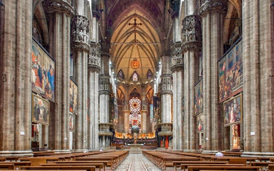 Interiors of the Duomo Milan Cathedral with ornate columns and stained glass windows.