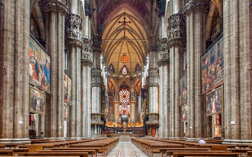 Interiors of the Duomo Milan Cathedral with ornate columns and stained glass windows.