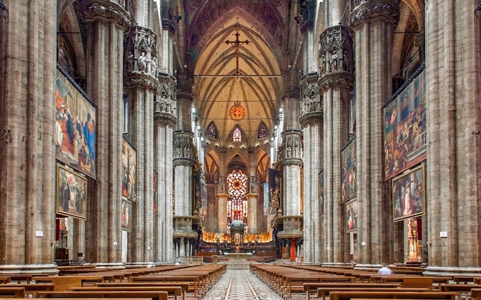 Interiors of the Duomo Milan Cathedral with ornate columns and stained glass windows.
