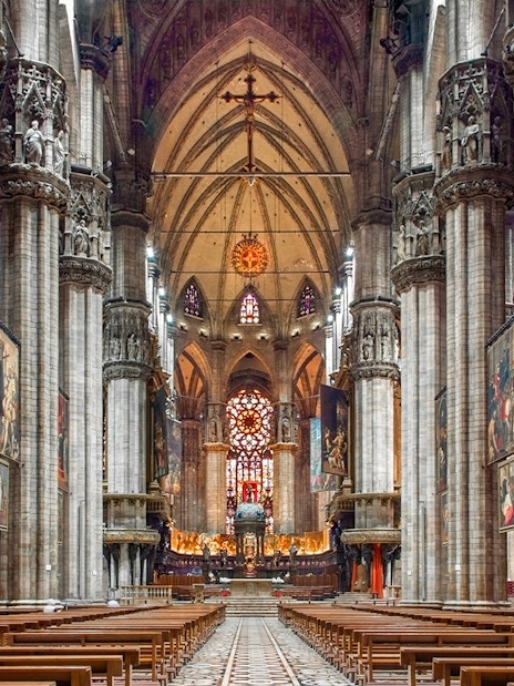 Interiors of the Duomo Milan Cathedral with ornate columns and stained glass windows.
