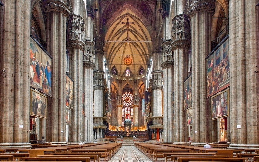 Interiors of the Duomo Milan Cathedral with ornate columns and stained glass windows.
