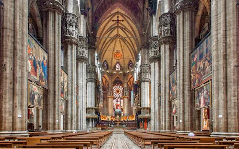 Interiors of the Duomo Milan Cathedral with ornate columns and stained glass windows.