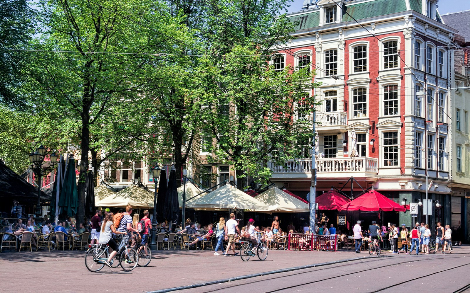 Bicyclists and people at outdoor cafes in Amsterdam's Leidseplein.