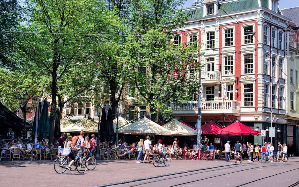 Bicyclists and people at outdoor cafes in Amsterdam's Leidseplein.