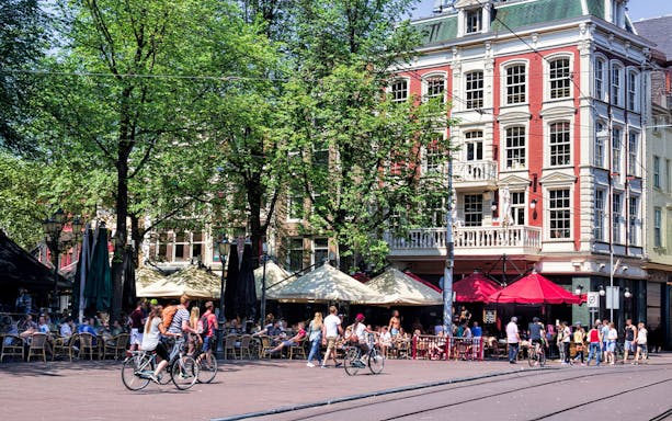 Bicyclists and people at outdoor cafes in Amsterdam's Leidseplein.