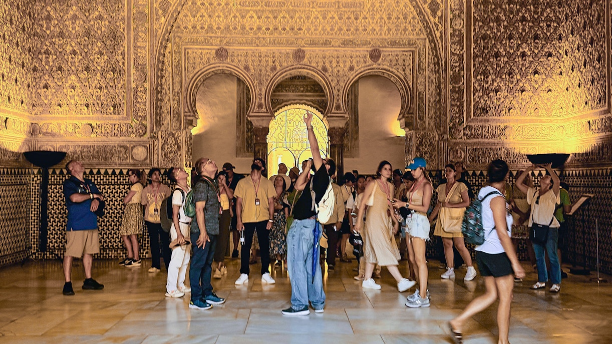 Tour guide leading a group of tourists through the stunning courtyards of Alcazar of Seville, showcasing the intricate Moorish architecture, on a Skip-the-Line Guided Tour