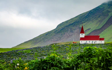 Church with red roof in Vik village, south Iceland, set against a green hillside.