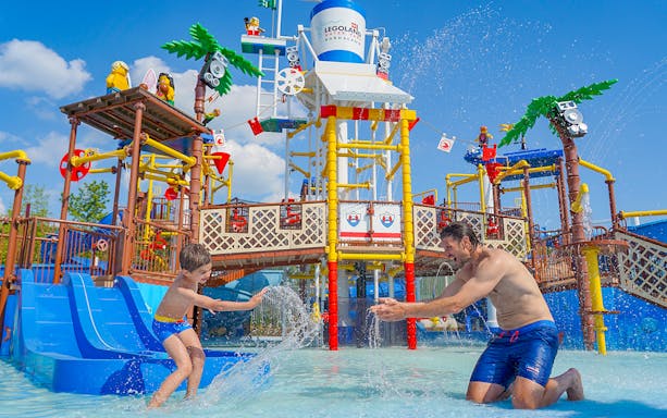 Child and adult playing at Legoland Water Park Gardaland beach party in Verona.