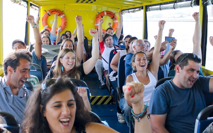 Tourists enjoying a lively boat ride on a Lisbon sightseeing guided tour.