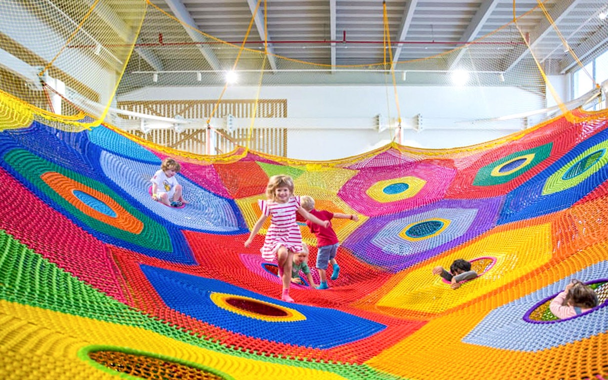 Children playing on colorful nets at Olioli Children's Play Museum, Dubai.