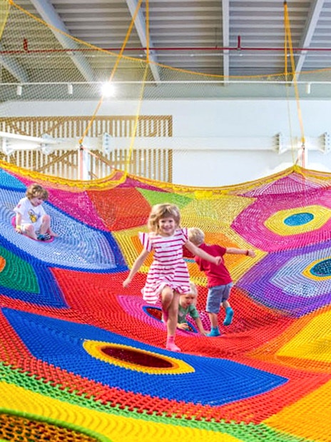 Children playing on colorful nets at Olioli Children's Play Museum, Dubai.