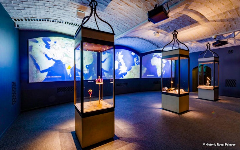 Exhibit room with illuminated display cases and world maps at Historic Royal Palaces.