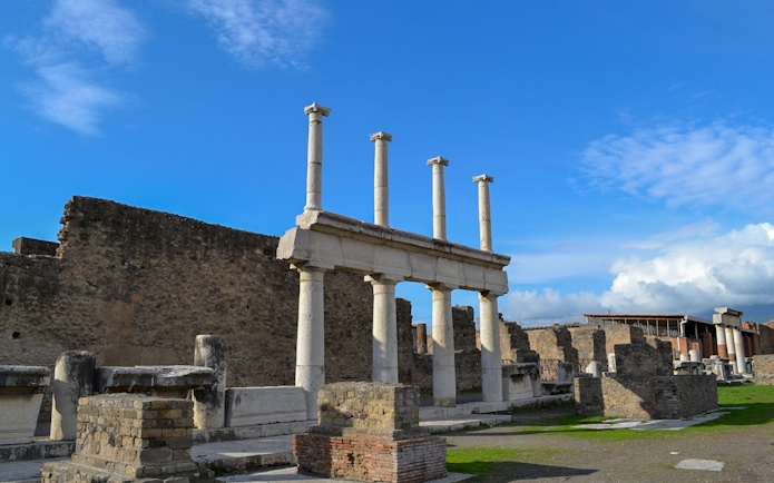 Ancient ruins with columns in Pompeii under a blue sky.