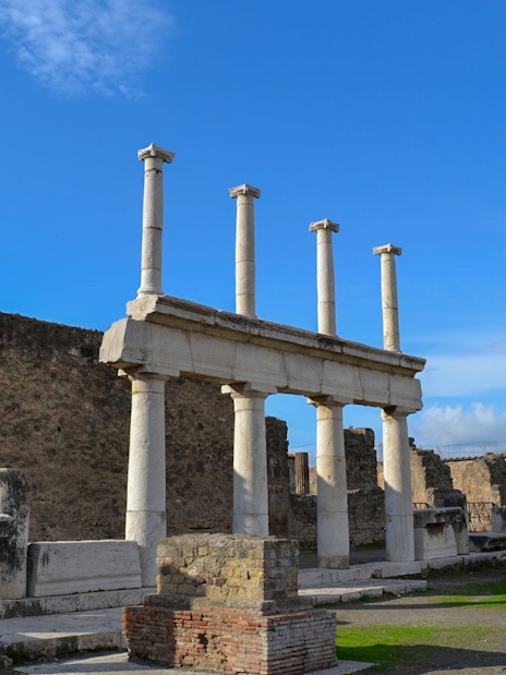 Ancient ruins with columns in Pompeii under a blue sky.