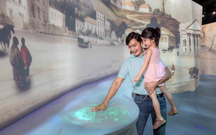 Family exploring interactive exhibit inside the Time Capsule, Singapore.