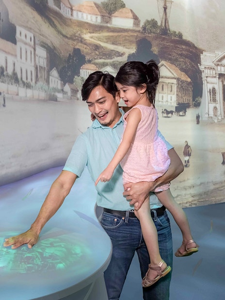 Family exploring interactive exhibit inside the Time Capsule, Singapore.