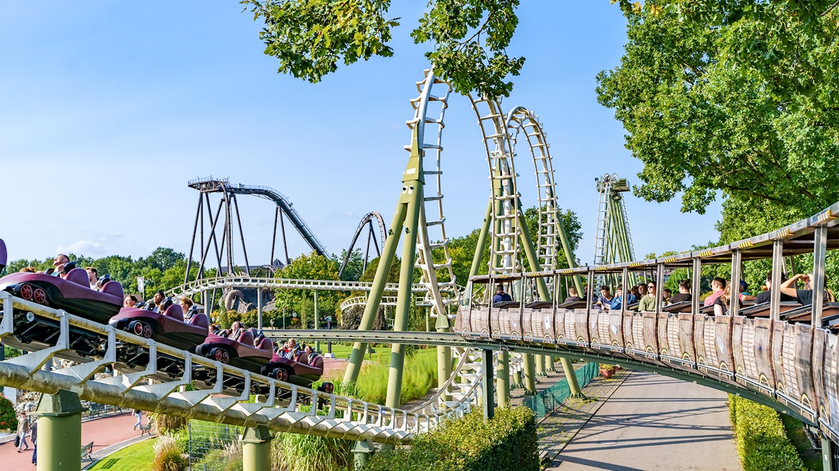 Rollercoaster with big loops at Heide Park Resort, Hamburg, surrounded by trees and riders.