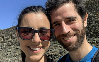 Couple smiling in front of ancient stone wall in Porto during self-guided city exploration game.