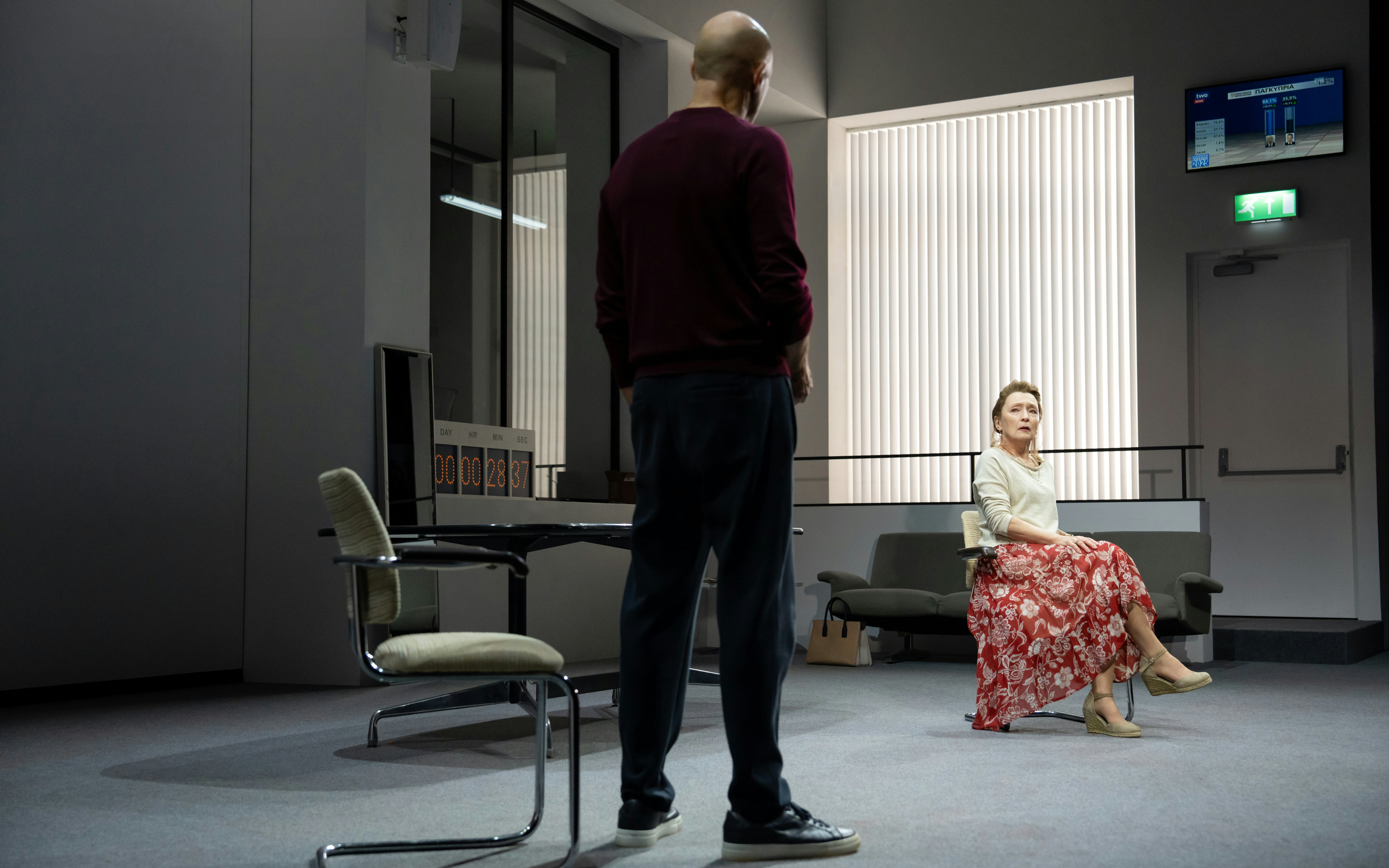 Stage scene with two actors at Oedipus Broadway show, one seated, one standing.