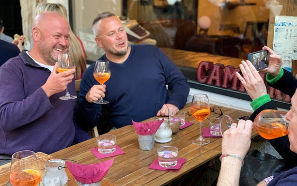 Group enjoying Aperol Spritz at a café in Venice during the Ultimate Spritz Tour.