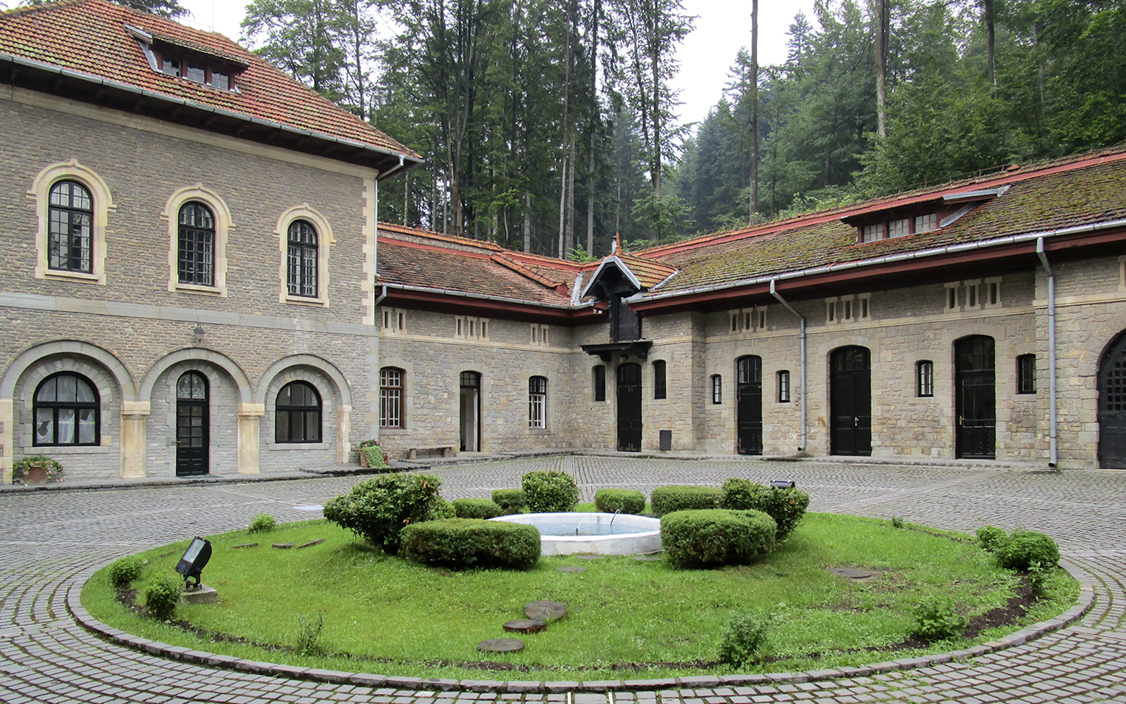 Courtyard view inside Cantacuzino Palace with stone buildings and central garden.