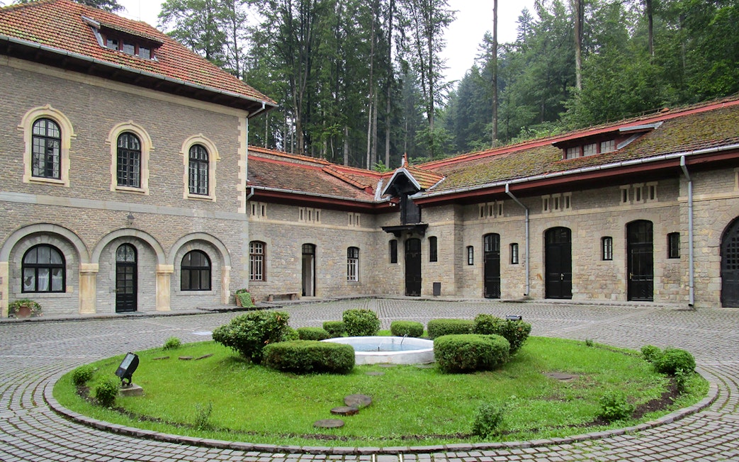 Courtyard view inside Cantacuzino Palace with stone buildings and central garden.