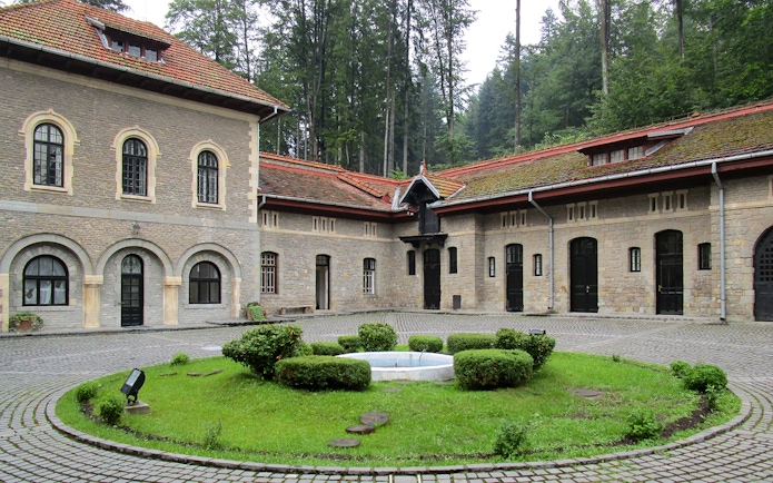 Courtyard view inside Cantacuzino Palace with stone buildings and central garden.