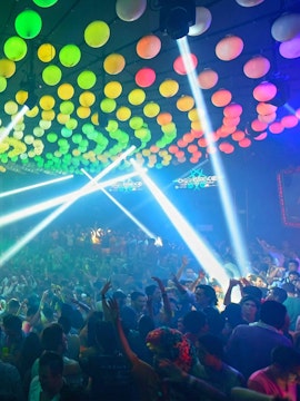 Crowded dance floor with colorful lights at Mandala Nightclub, Cancun.