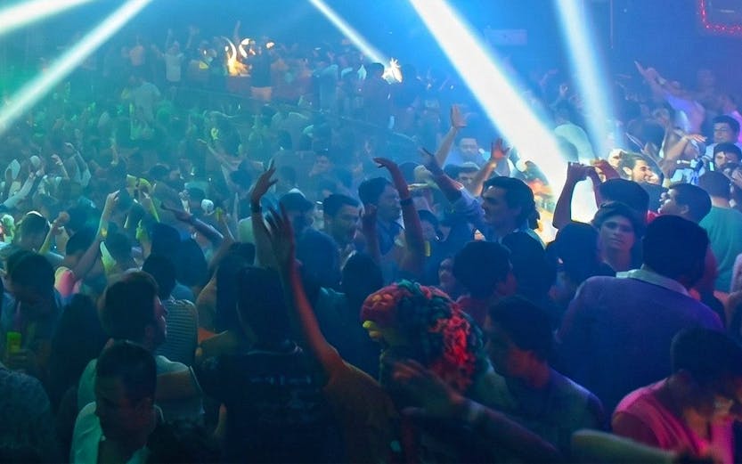 Crowded dance floor with colorful lights at Mandala Nightclub, Cancun.