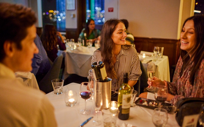 Guests enjoying dinner and drinks on the Showboat Vivid Sydney cruise with live cabaret.