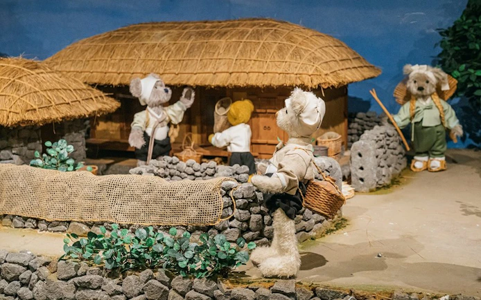 Teddy bears in traditional attire at a village scene, Teddy Bear Museum.