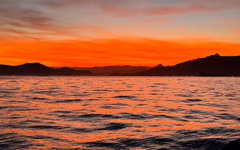 Sunset over the ocean with distant hills in Arraial do Cabo, Brazil.