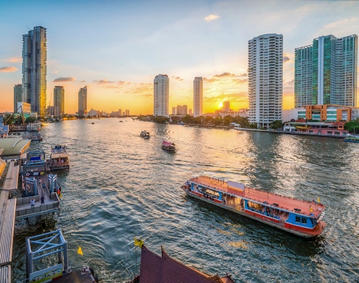 River Star Princess cruising on Chao Phraya River at sunset, Bangkok skyline in background.