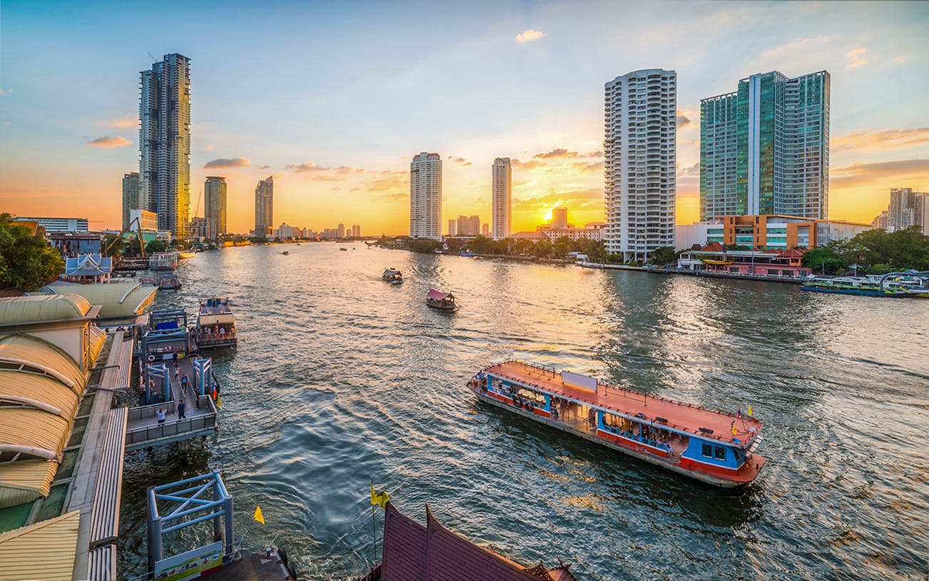 River Star Princess cruising on Chao Phraya River at sunset, Bangkok skyline in background.