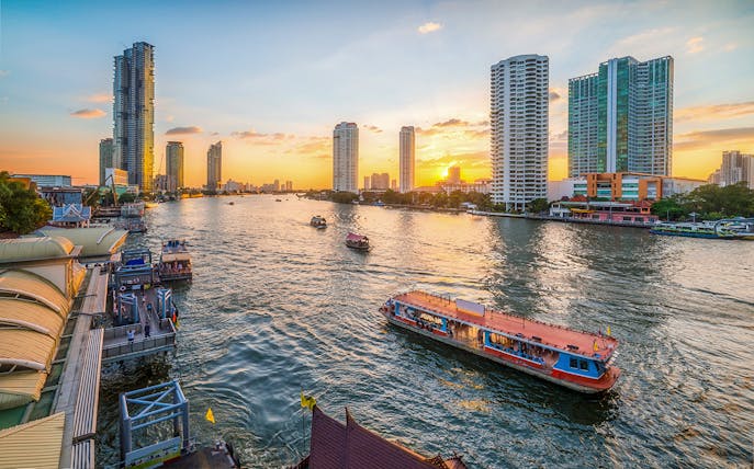 River Star Princess cruising on Chao Phraya River at sunset, Bangkok skyline in background.