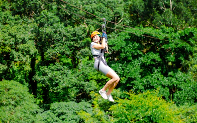 Person ziplining through lush forest canopy in Koh Samui.