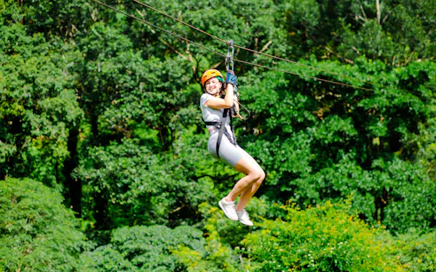Person ziplining through lush forest canopy in Koh Samui.