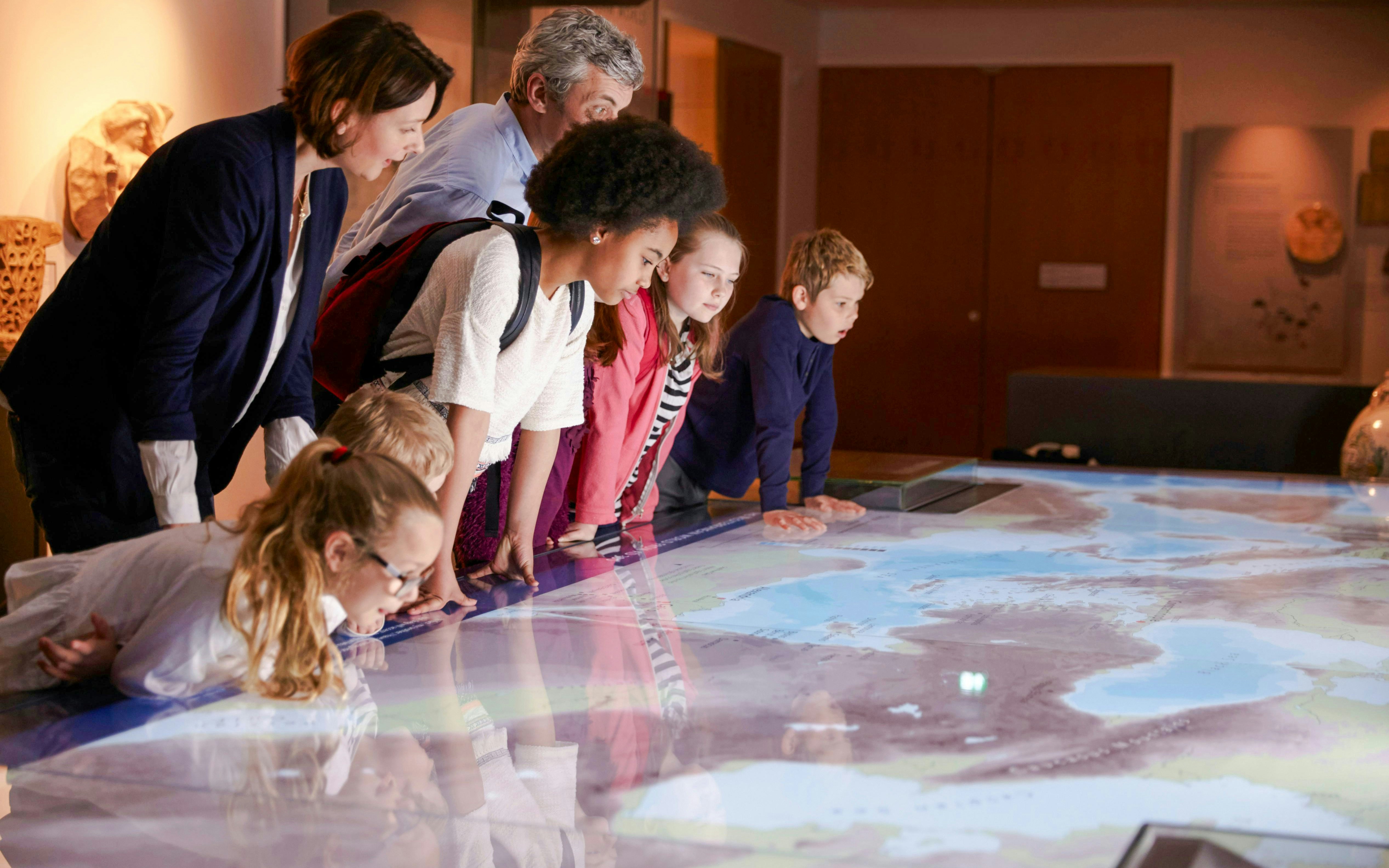 Visitors engaging with interactive map exhibit at Les Invalides, Paris.