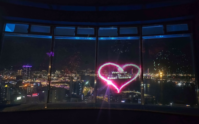 Busan Tower observatory view with city lights and heart-shaped welcome sign.