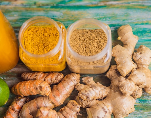 Traditional Balinese spices with turmeric, ginger, and lime on a wooden surface.
