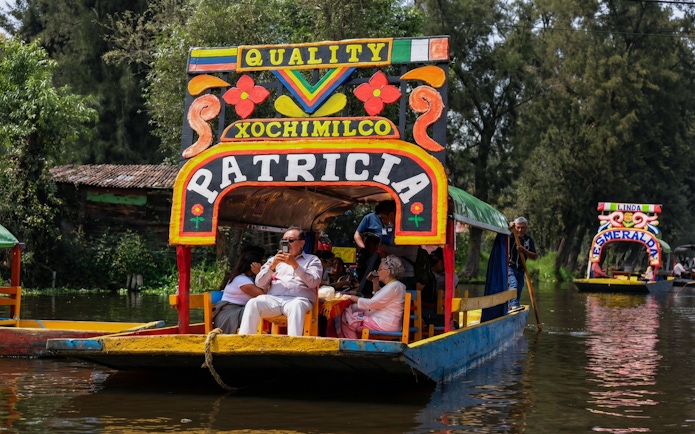 Xochimilco trajinera with tourists enjoying a canal ride in Mexico City.