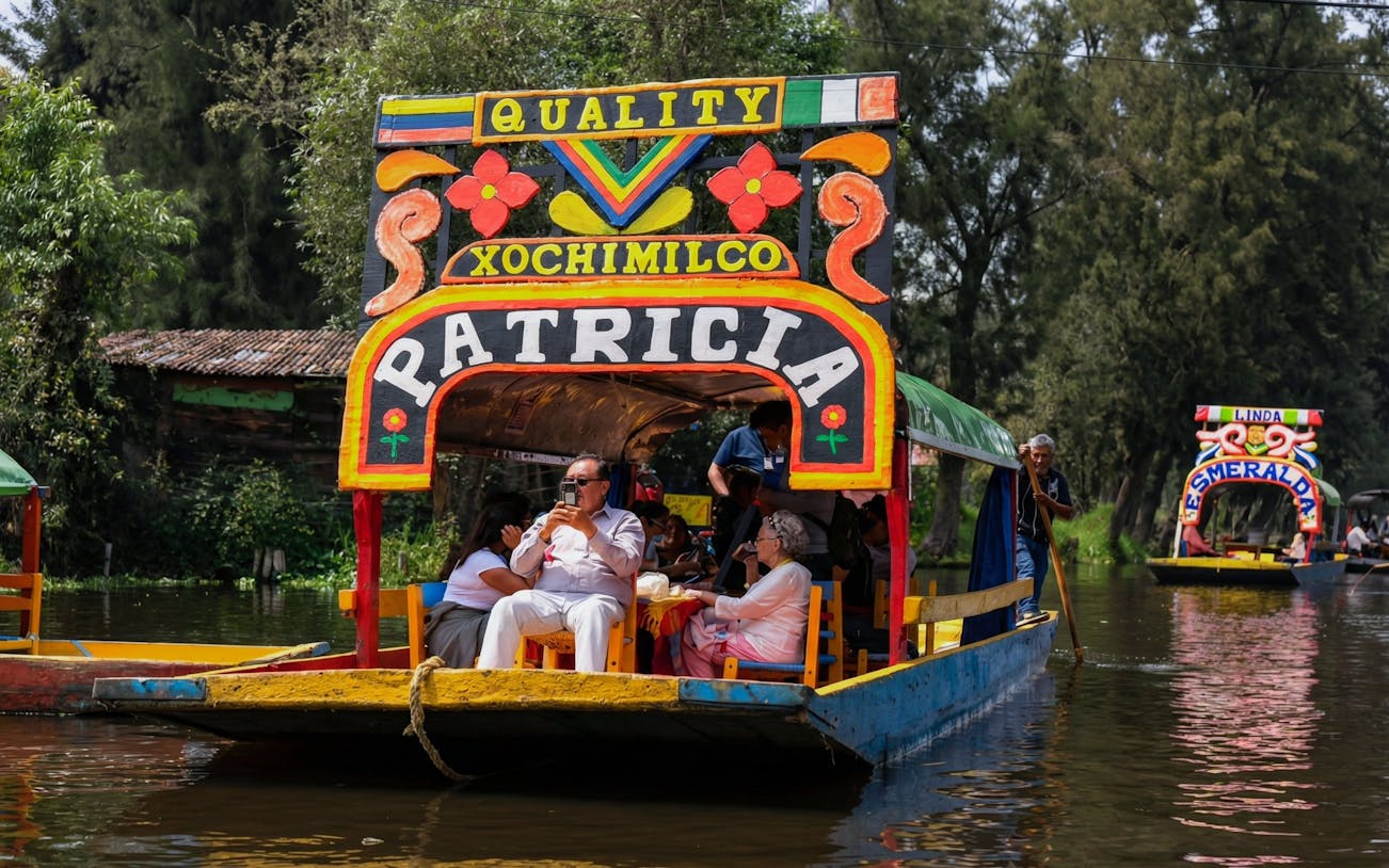 Xochimilco trajinera with tourists enjoying a canal ride in Mexico City.